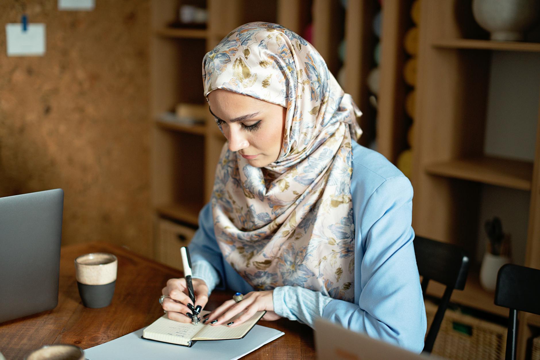 woman sitting while writing on a small notebook