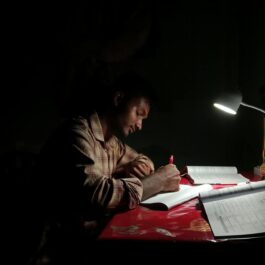 young man studying at night with lamp light